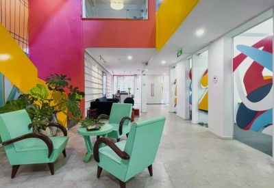 Bright reception lounge with mint green armchairs and colorful abstract wall graphics.