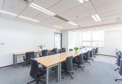 Bright open-plan office featuring long shared desks and natural light.