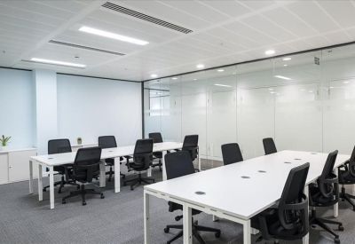 Bright open-plan office space with rows of white desks and ergonomic black chairs.