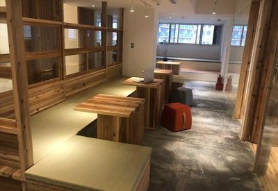 Modern coworking area featuring warm wooden seating platforms and colorful ottoman stools.