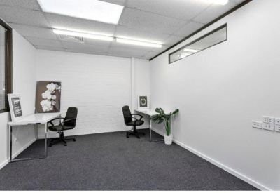 Private office space featuring two white desks and black swivel chairs.
