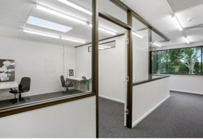 Glass-walled internal office suite viewed from a carpeted hallway.