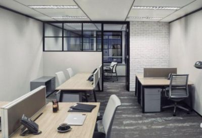 Modern office suite with several wooden desks, ergonomic chairs, and glass partitions.