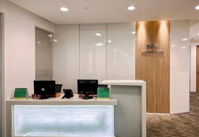Modern reception desk with a backlit frosted glass front and wooden accent wall.