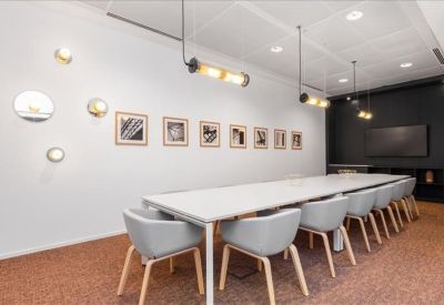 Meeting room with long white table, grey chairs, and circular wall art.
