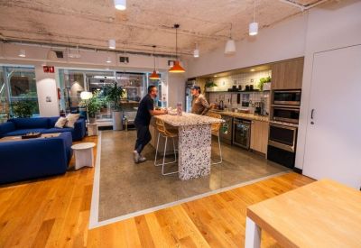 Modern kitchen and dining area with a high marble island and blue velvet sofas.