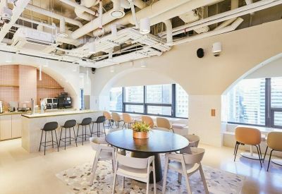 Bright breakout space with a round meeting table, bar seating, and large windows.