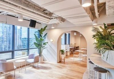Modern reception area with an arched doorway leading to a brightly lit workspace and lounge chairs.
