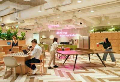 Vibrant communal area featuring a ping pong table, lounge seating, and a neon wall sign.