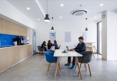 Vibrant communal kitchen and breakout area with wooden cabinetry and blue feature wall.