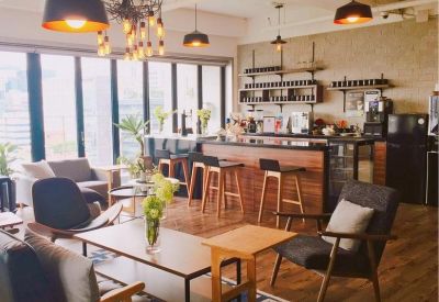 Lounge area with mid-century modern furniture, wooden floors, and a bar counter under warm lighting.