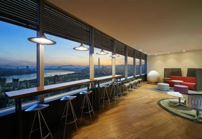 Coworking lounge area with high stools and a long wooden counter overlooking the city river.