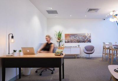 Modern office reception or lounge area with a desk, laptop, and comfortable seating.