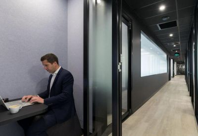Private phone booth or focus pod in a quiet corridor with wood-look flooring.