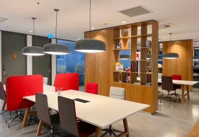 Spacious coworking area at 525 Collins Street, Rialto M2, West Podium with white tables and vibrant red chairs.