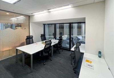 Modern meeting room featuring a long white table, black mesh chairs, and a glass wall.