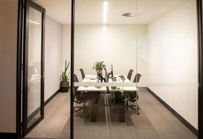 Bright glass-enclosed meeting room with a central white table and minimalist decor.