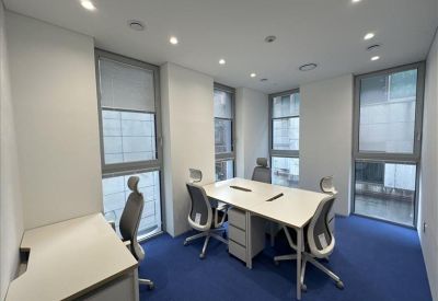 Private office suite with two desks, ergonomic chairs, blue carpeting, and large windows.