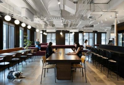 Large communal cafe and coworking space with long wooden tables and industrial ceilings.