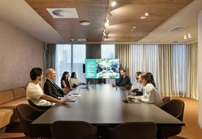 Professional meeting room with a large boardroom table and integrated video conferencing screen.