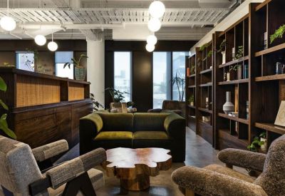 Relaxed lounge area with green velvet sofa, fuzzy armchairs, and a large wooden bookshelf.