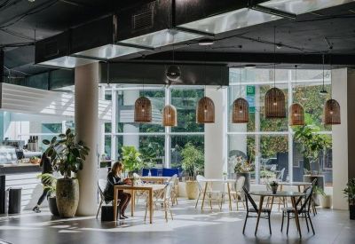 Spacious communal dining and cafe area with woven pendant lights and large windows.
