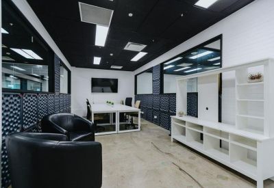 Modern office suite with black leather armchairs, white workstations, and a storage unit.