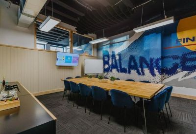 Professional meeting room featuring a long wooden table, blue velvet chairs, and a balance mural.