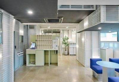 Reception area with a light green front desk and self-service kiosks.