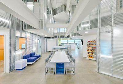 Modern meeting area featuring a long white table with a blue base and multiple chairs.