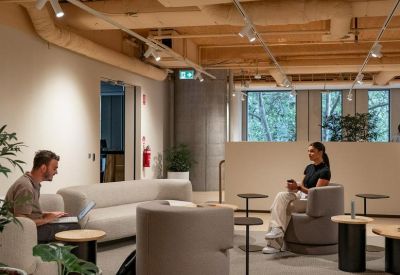 Spacious communal lounge featuring modern armchairs, wooden ceilings, and exposed ductwork.