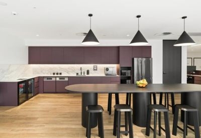 Modern kitchen and breakout area with plum cabinetry and a large oval island.
