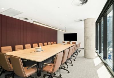 Large boardroom featuring a long light-wood table and tan leather chairs.