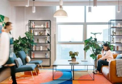 Bright breakout area with blue armchairs, a colorful rug, and floor-to-ceiling windows.