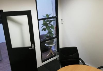 Private office nook featuring a round table and a view through a window to an indoor plant.