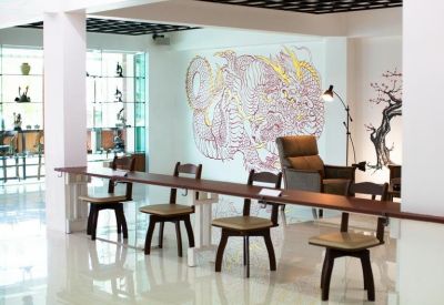 Communal workspace area featuring a long wooden counter and wall art of a dragon.