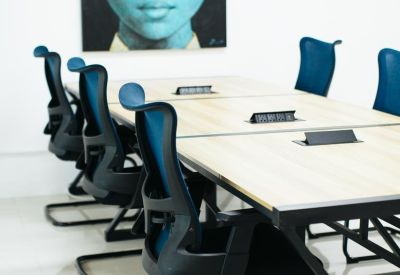 Meeting room with light wood table, black chairs, and a portrait of a blue-toned face.