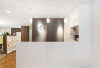 Clean white reception desk with modern pendant lighting and branded wood-paneled backdrop.
