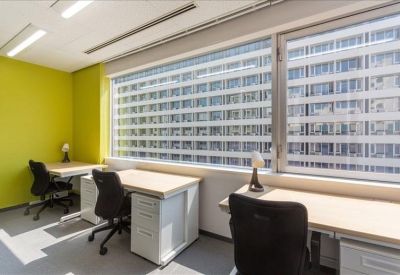 Bright private office with white desks, black ergonomic chairs, and a lime green accent wall.