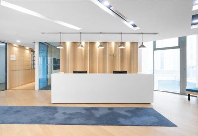 Clean, minimalist reception area featuring a white desk and warm wood-paneled wall.