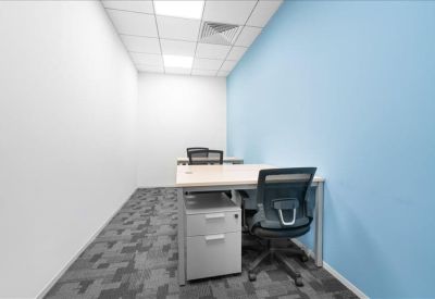 Private windowless office with a light blue accent wall and two workstations.