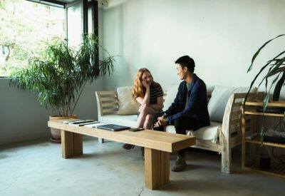 Communal lounge with a long wooden coffee table, white sofa, and large indoor plants.