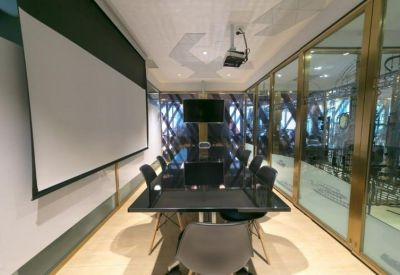 Modern conference room featuring a large projection screen, glass walls, and a black meeting table.