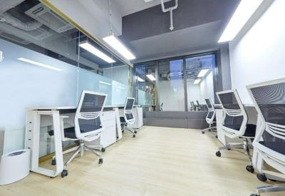 Bright open-plan workspace with white desks, ergonomic mesh chairs, and glass partitions.