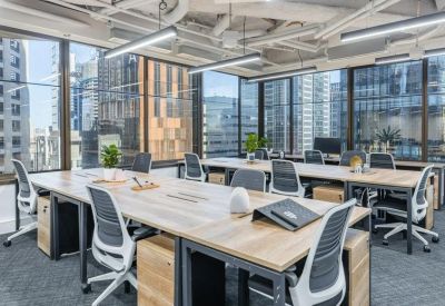 Open-plan workspace with wooden desks, ergonomic chairs, and large windows overlooking the city.