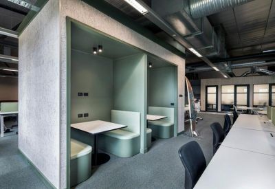 Semi-enclosed green privacy booths with white tables and integrated seating.