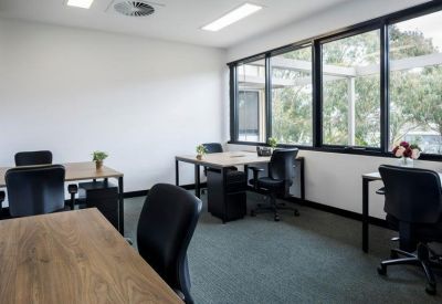 Sunlit private office space with three timber desks and ergonomic black chairs.