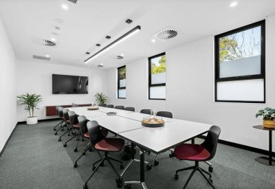 Bright conference room with a long white table, burgundy chairs, and large windows.