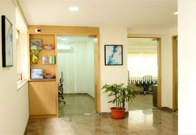 Reception area with wooden shelving, a potted plant, and a framed abstract painting.