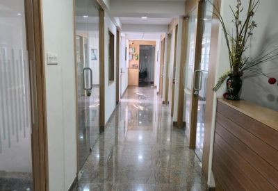 Brightly lit office corridor with polished stone floors and glass office partitions.